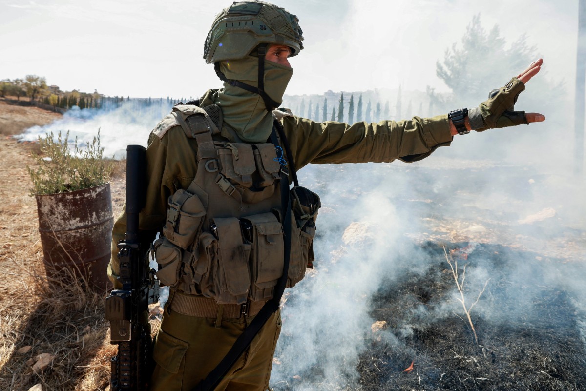 An Israeli soldier gestures after pushing away Palestinian farmers and foreign activists (AFP)