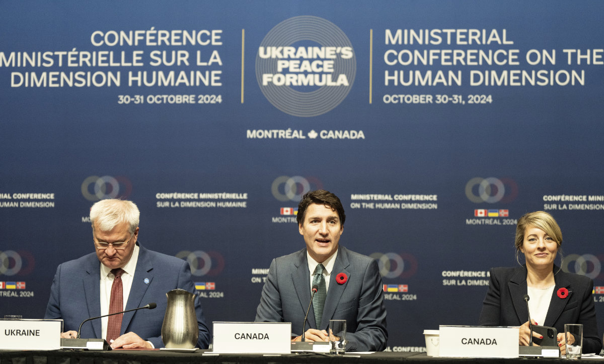 Canadian Prime Minister Justin Trudeau, center, flanked by Ukraine Minister of Foreign Affairs Andrii Sybiha, left, and Canada's Minister of Foreign Affairs Melanie Joly, gives opening remarks during a plenary session for the Ministerial Conference on the Human Dimension of Ukraine's 10-Point Peace Formula, in Montreal on Oct. 31, 2024. (The Canadian Press via AP)