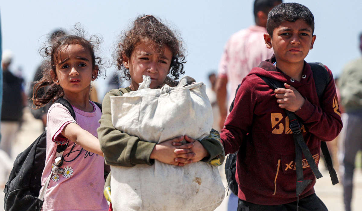 Children walk with other displaced Palestinians as they pass through Nuseirat in the central Gaza Strip on April 14, 2024. (AFP)