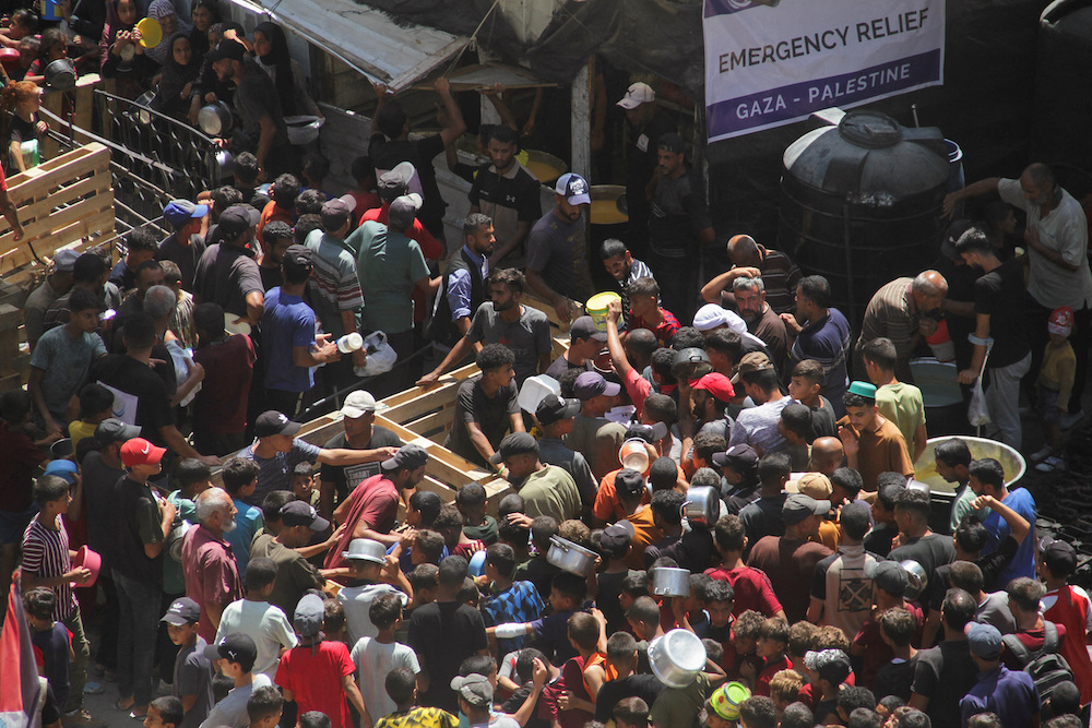 Palestinians gather to receive food cooked by a charity kitchen, amid Israel-Hamas conflict, in Jabalia. (Reuters)