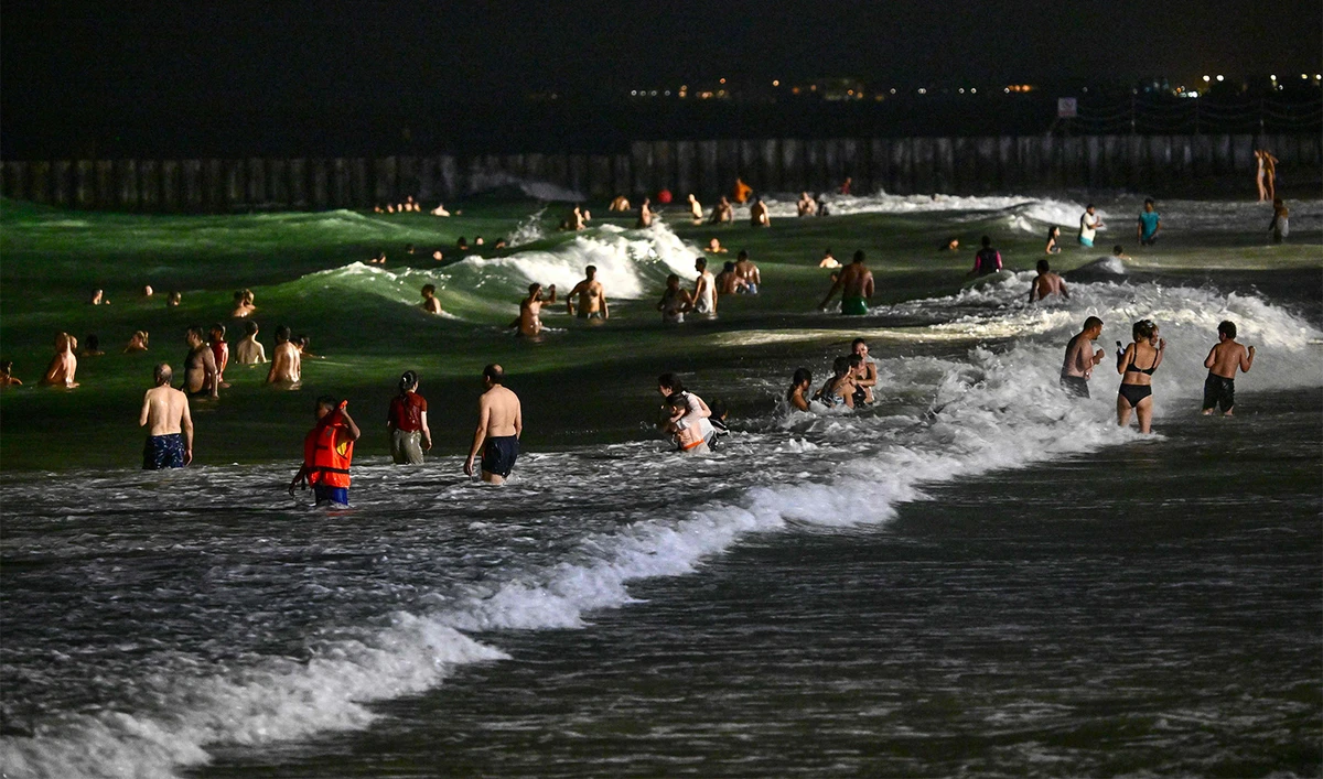 People swim at the Umm Suqeim beach in Dubai during the night of October 5, 2024. (AFP)