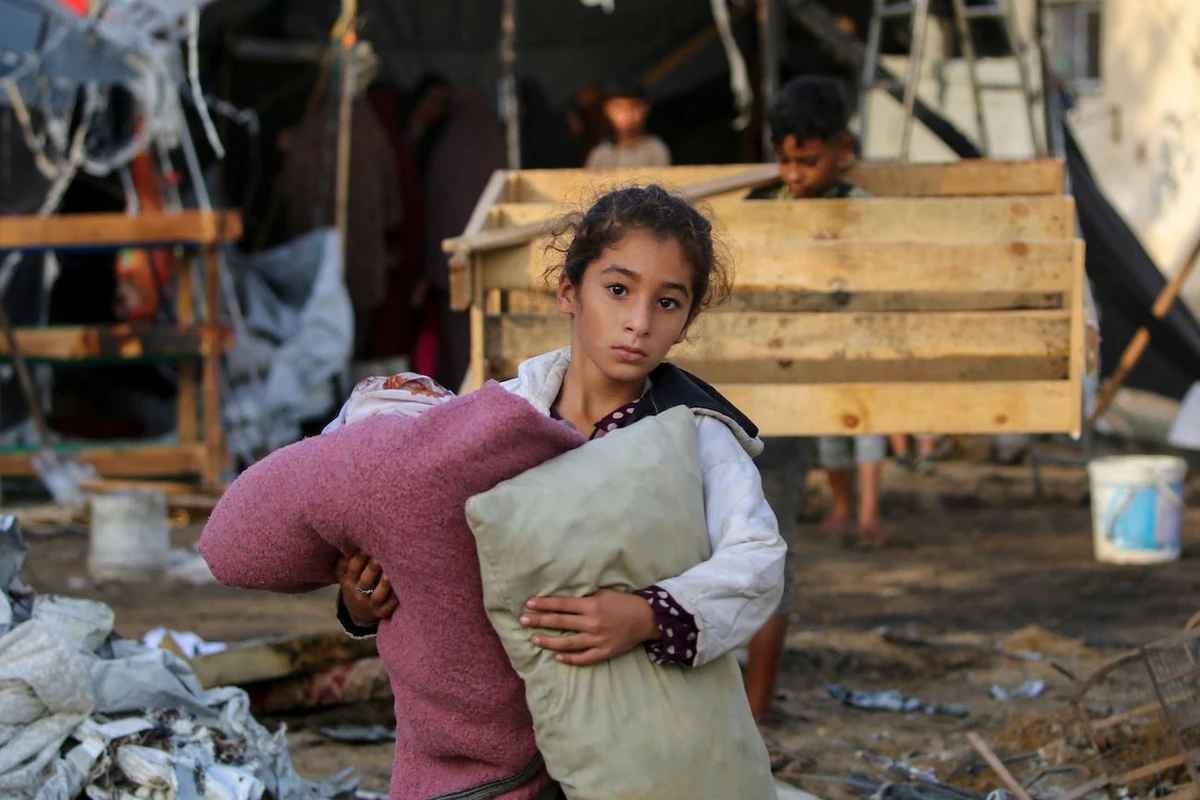 A child carries salvaged items following an Israeli air strike the previous night on the Bureij refugee camp in the central Gaza Strip on October 8, 2024. (AFP)