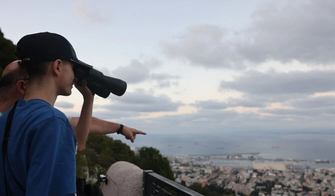 A young boy uses binoculars to watch the port of Haifa from a lookout on October 11, 2024. (AFP)
