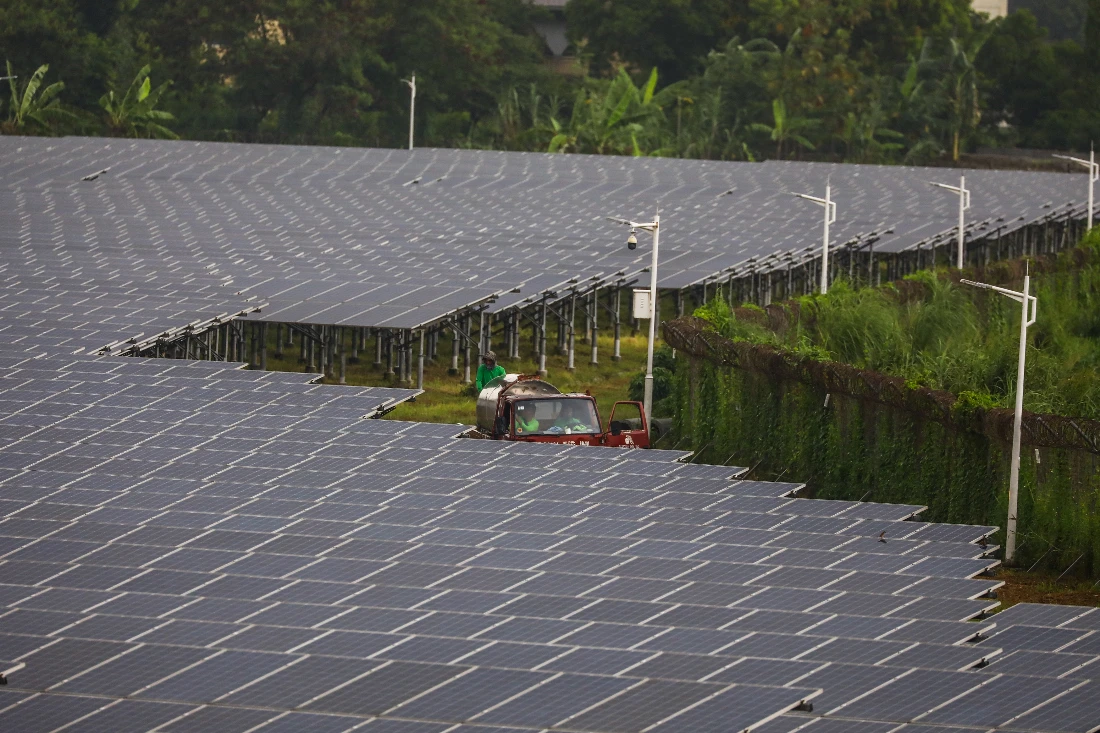 Workers in a utility truck ride past solar panels at a solar energy farm in Valenzuela, suburban Manila. (AFP/File)