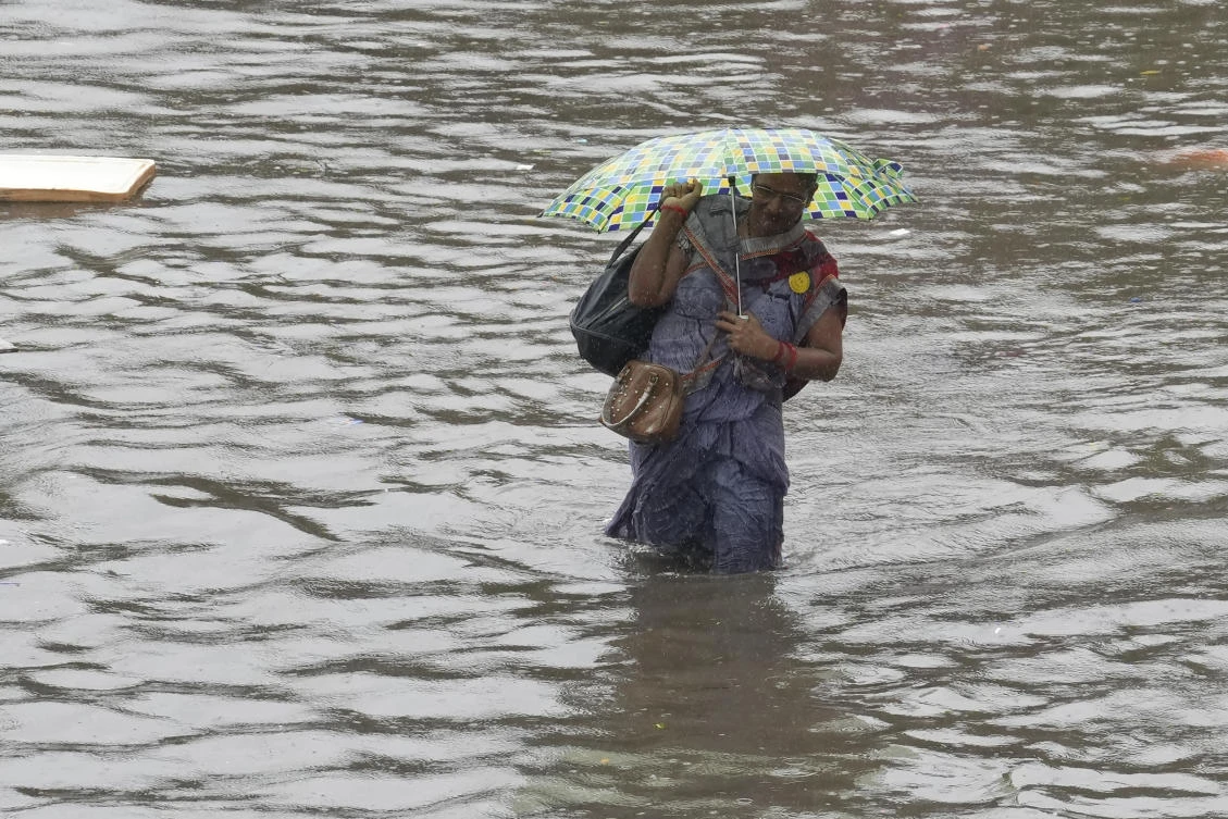 Above, a woman wades through a flooded street during heavy rain in Chennai on Oct. 15, 2024. (AP)