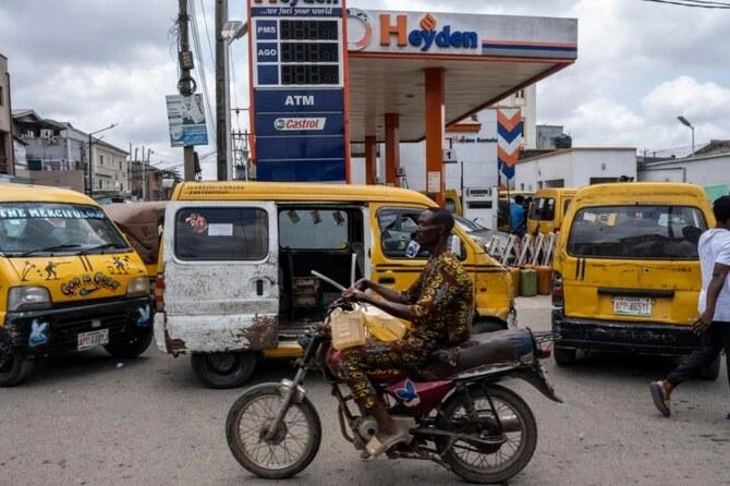 A man holds jerrycans as he rides his motorbike past a fuel station in Lagos, on September 4, 2024. (AFP)