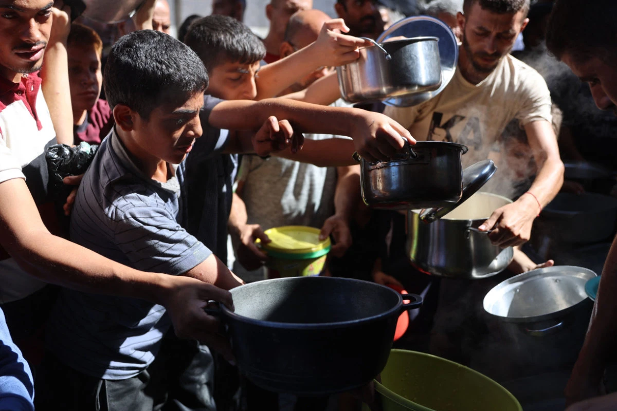 Displaced Palestinians queue to receive food rations, offered by a charity, in Gaza's Al-Shati refugee camp on October 17, 2024. (AFP)