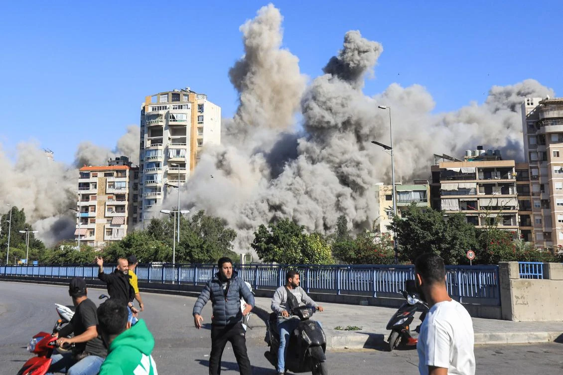 People watch as a smoke cloud erupts after a rocket fired by an Israeli war plane hit a building in Beirut’s southern suburb of Shayah on October 22, 2024. (AFP)