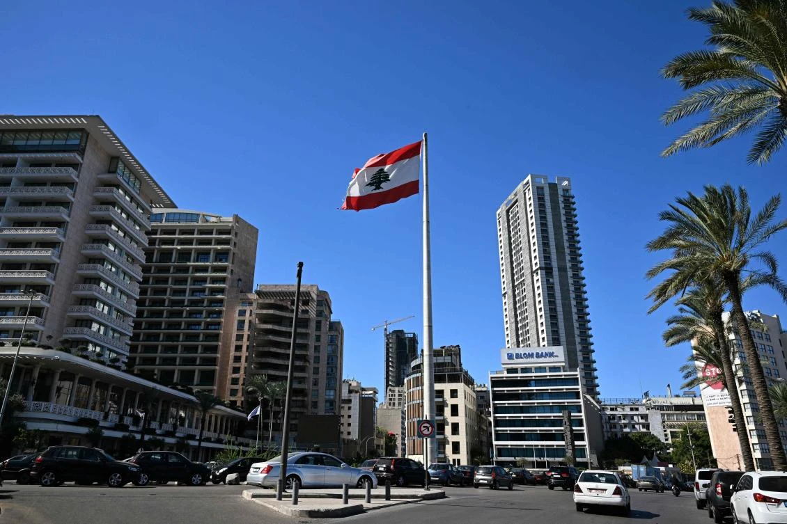 People drive past a Lebanese national flag fluttering in a square in central Beirut on Oct. 21, 2024, amid the ongoing Israel-Hezbollah war. (AFP)