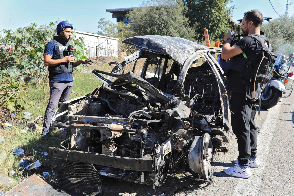 Journalists and security forces stand next to the wreckage of a car that was targeted in an Israeli drone attack on the Beirut-Damascus road in the area of Kahhale on October 24, 2024, amid the ongoing war between Israel and Hezbollah. (AFP)