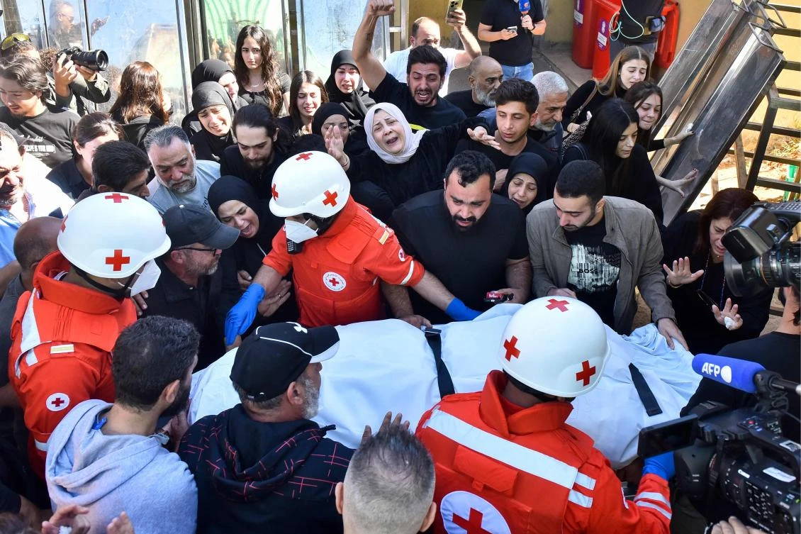 Relatives and colleagues of three journalists killed in an Israeli strike in the southern Lebanese village of Hasbaya gather around a Red Cross ambulance as their bodies arrive at a hospital in Beirut on Oct. 25, 2024. (AFP)