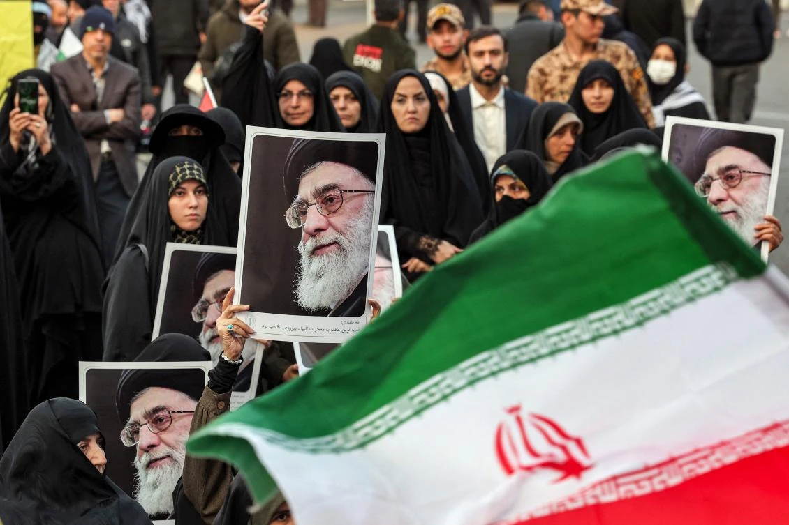 An Iranian flag flies before women demonstrators holding up pictures of Iran's Supreme Leader Ayatollah Ali Khamenei during an anti-Israel rally in Tehran. (File/AFP)