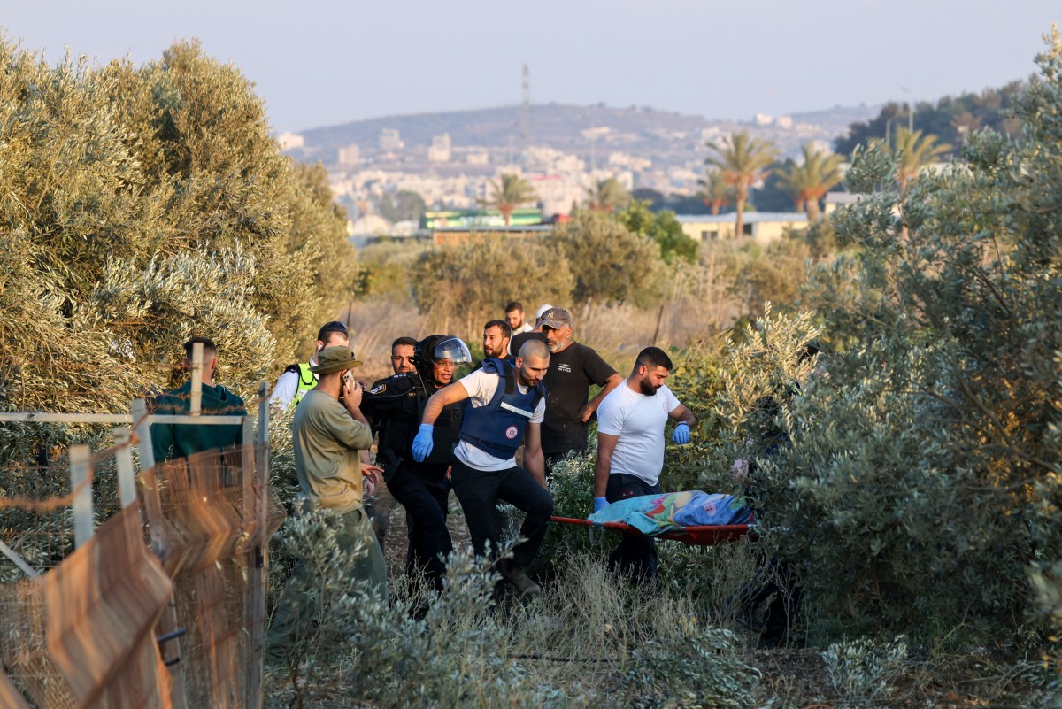 First responders carry the shrouded body of a woman who was killed when a rocket fired from Lebanon hit an area near Kiryat Ata in northern Israel's Haifa district on October 31, 2024, amid the ongoing war between Israel and Hezbollah (AFP)