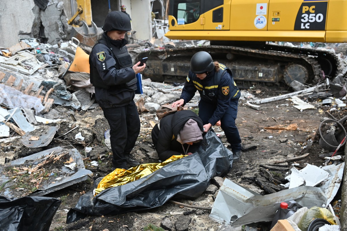 Ukrainian law enforcement officers comfort a woman crying over the body of her 15-year-old son following a missile attack in Kharkiv on October 31, 2024 (AFP)