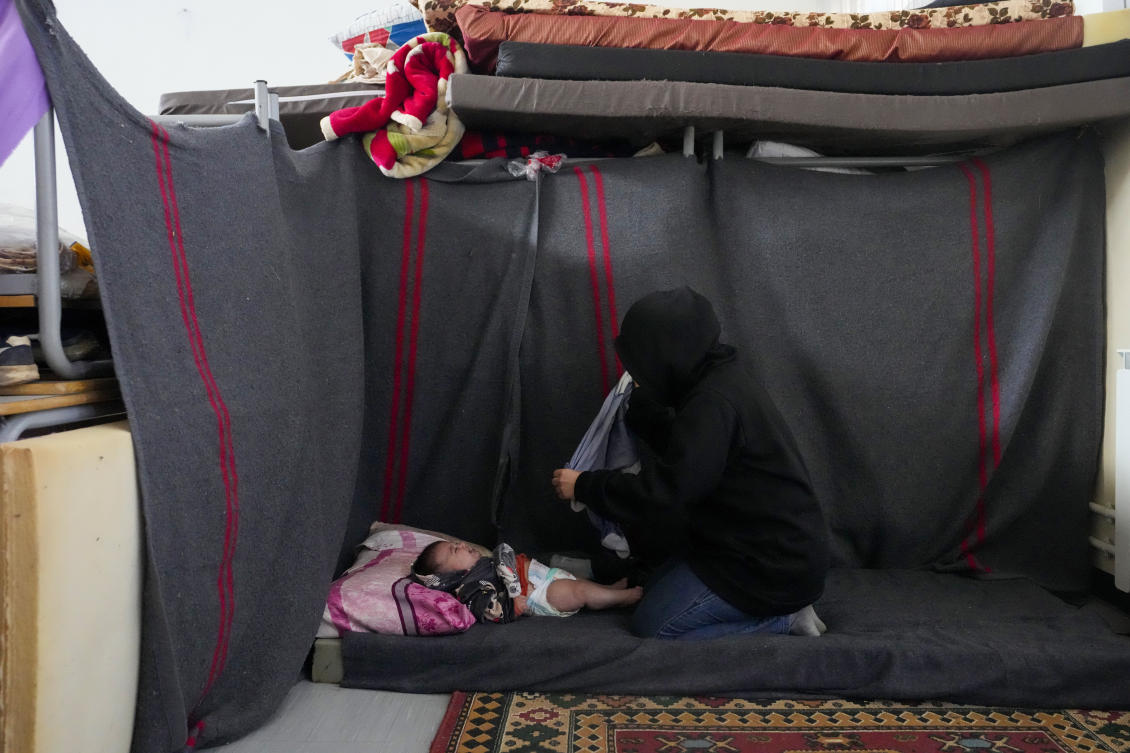 A displaced woman, who fled Baalbek city and the nearby towns of Douris and Ain Bourday amid the ongoing Hezbollah-Israel war, changes the diaper of her daughter at a school being used as a shelter, in Deir Al-Ahmar, east Lebanon (AP)