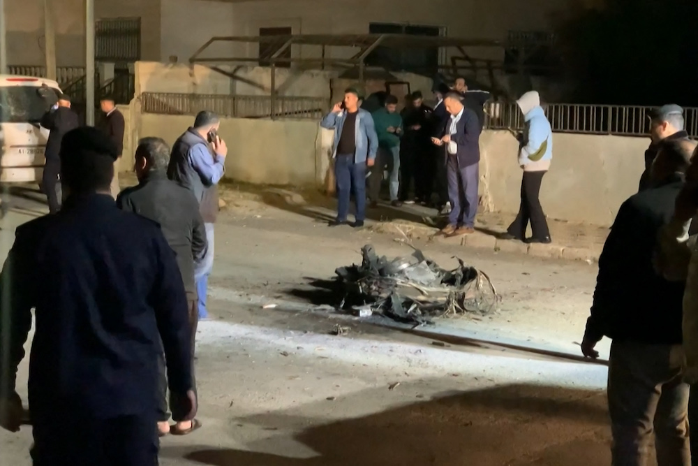 Above, residents and security agents stand around the debris of a missile that the Jordanian forces intercepted over Amman in the early hours of April 14, 2024. (AFP file photo)