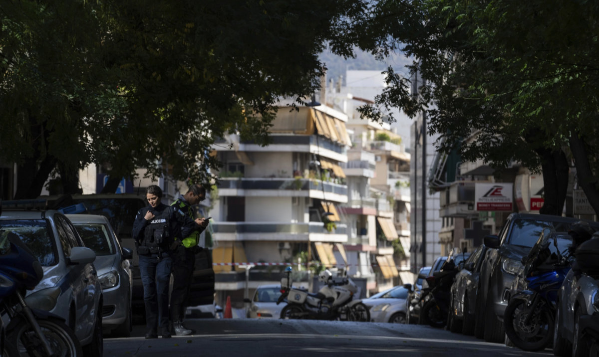 Police officers guard near the entrance of a building following an explosion, which police believe was caused by an improvised device, that killed a man and a woman was seriously wounded, in Athens on Nov. 1, 2024. (AP)