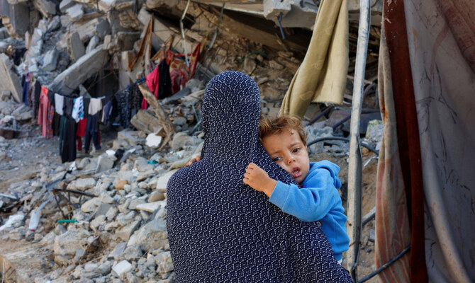A Palestinian woman carries her child near the ruins of a house destroyed in the Israeli military offensive, amid the Israel-Hamas conflict, in Khan Younis in the southern Gaza Strip, November 4, 2024. (Reuters)