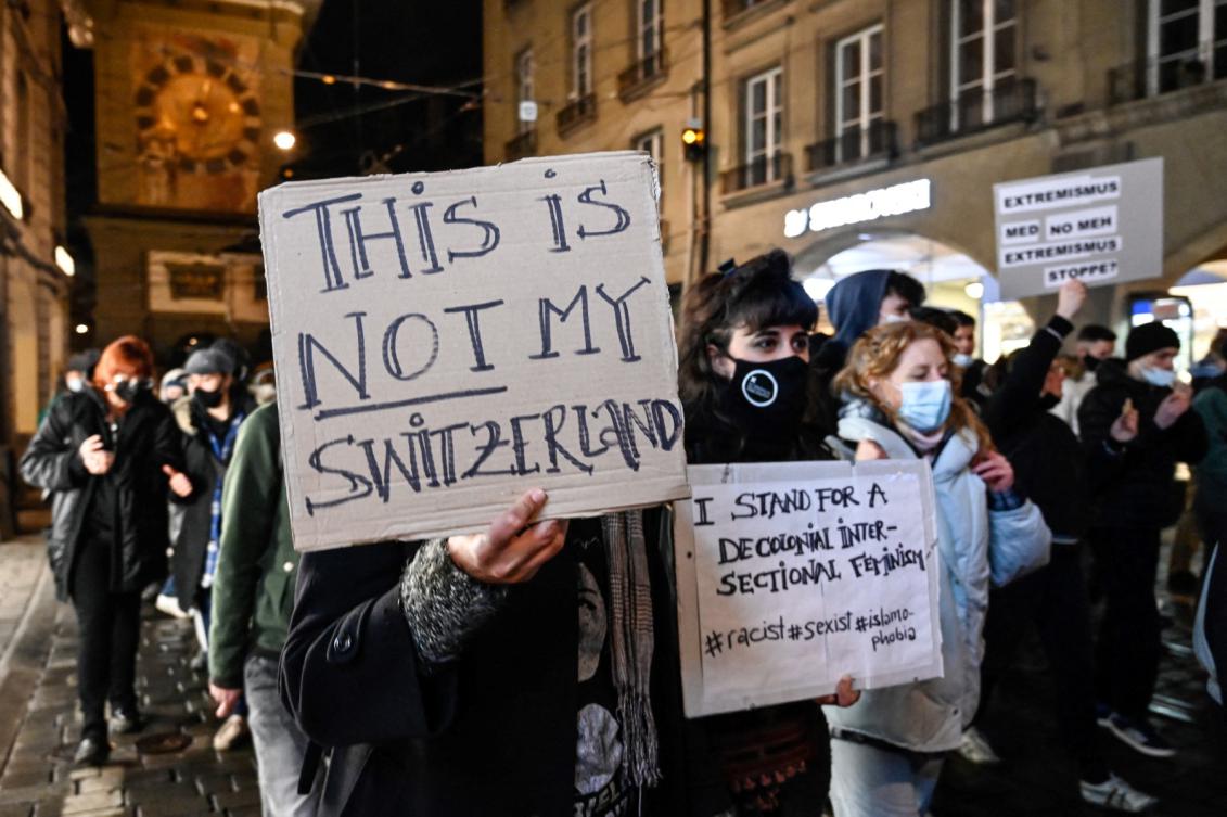 People hold signs during a protest hours after Swiss voters accepted an initiative, the so-called anti-burqa vote, to ban full facial coverings in public places in Bern on March 7, 2021. (File/AFP)
