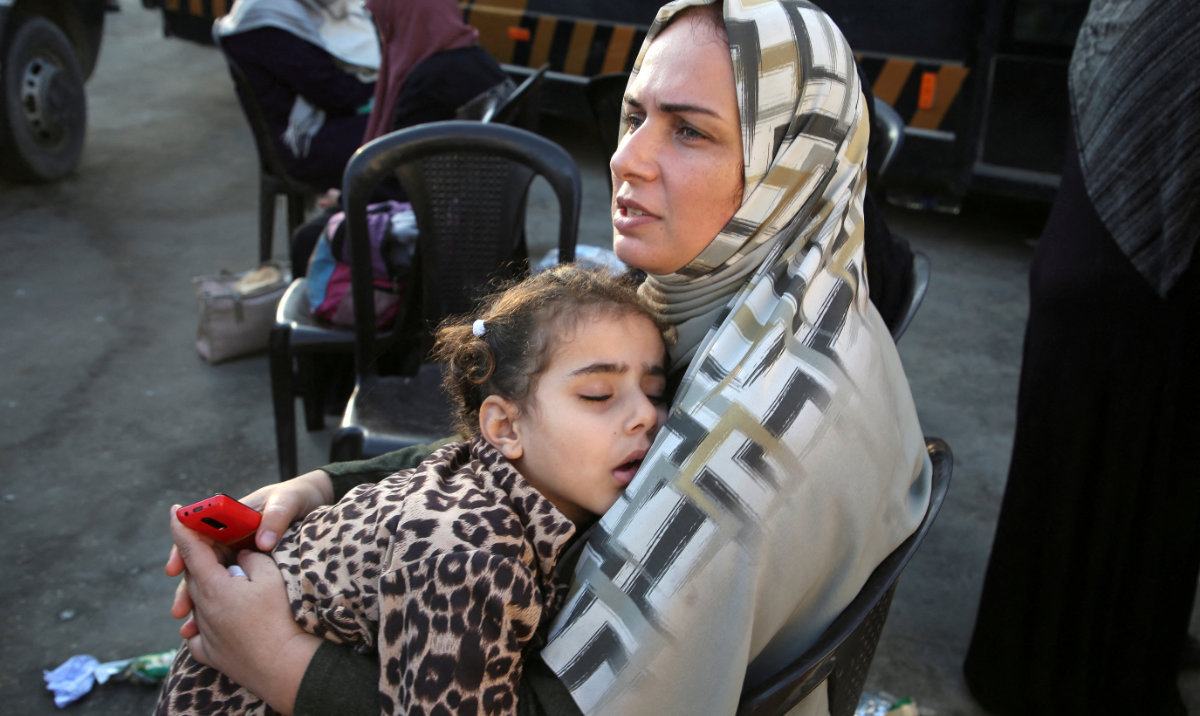 A Palestinian woman holds a sleeping child as people say goodbye to patients and the wounded before they are transferred for medical treatment abroad, amid the Israel-Hamas conflict, in Khan Younis in the southern Gaza Strip, November 6, 2024. (Reuters)