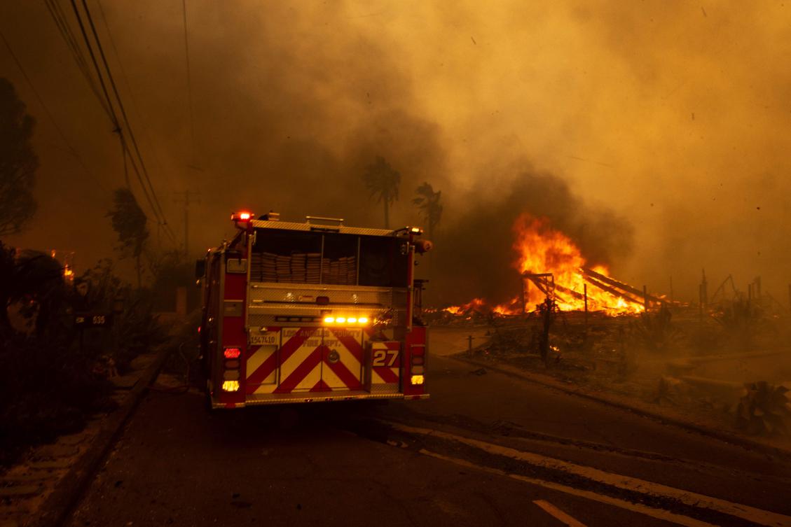 A house burns next to a firetruck as the Mountain Fire scorches acres in Camarillo Heights, Camarillo, California, on November 6, 2024. (AFP)