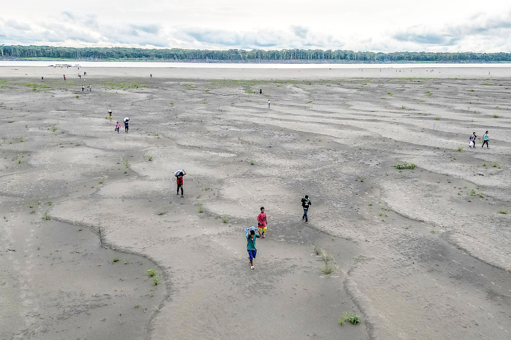 Aerial view of Yagua Indigenous people carrying water and other goods due to the low level of the Amazon river at Isla de los Micos, Amazonas department, Colombia. (AFP)