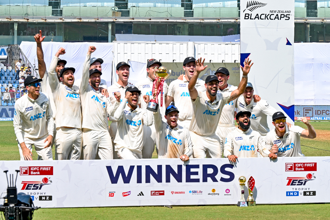 New Zealand players pose with the winner's trophy as they celebrate their team's victory against India at the end of their third and final Test cricket match in the Wankhede Stadium. (AFP)