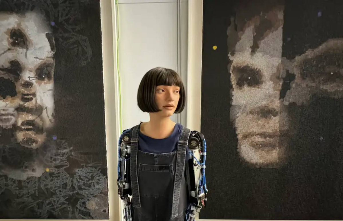Humanoid robot Ai-Da (center) is pictured with her painting of renowned English mathematician Alan Turing. (Social media photo)