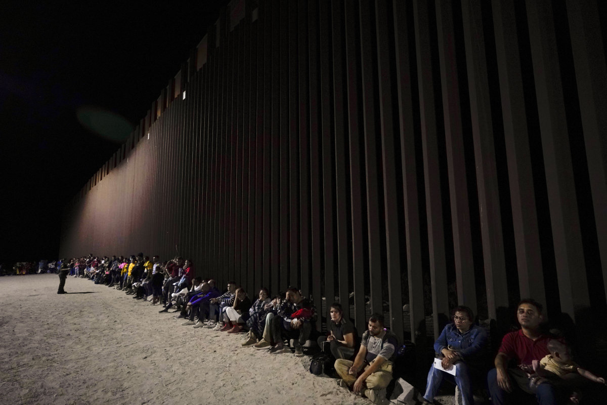 In this file photo, migrants wait to be processed after crossing into the United States near the end of a border wall near Yuma, Arizona. US president-elect Donald Trump has promised mass deportations of illegal immigrants once he sets foot at the White House. (AP)