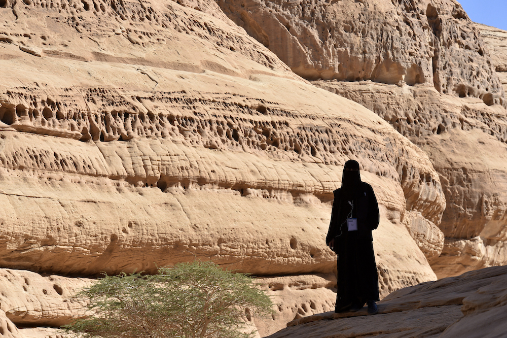 Above, a tourist poses in front of a rose-colored sandstone in Madain Saleh, a UNESCO World Heritage site, near Saudi Arabia’s northwestern town of AlUla. (AFP)