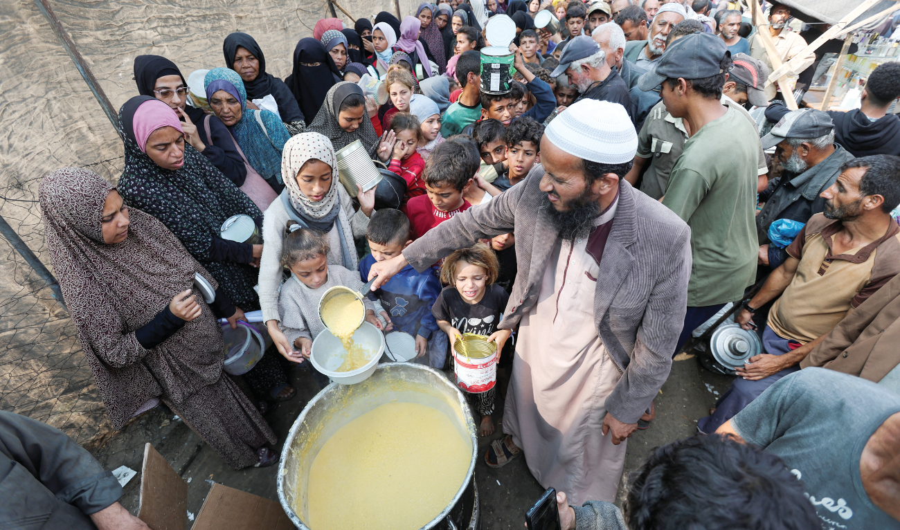 Palestinians gather to receive meals cooked by a charity kitchen in Deir Al-Balah, in the central Gaza Strip on Sunday amid the ongoing conflict between Israel and Hamas. (Reuters)
