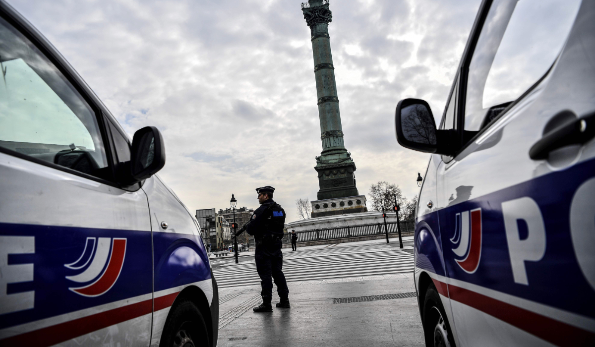 A French police officer stands by police vehicles during checks on drivers at Place de la Bastille in Paris on March 17, 2020. (AFP)