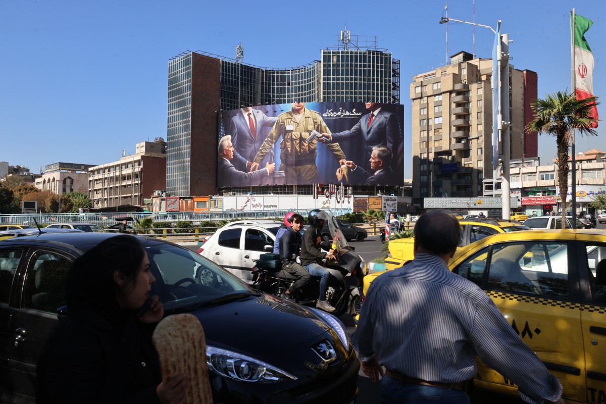 Iranian motorists drive past an anti-Israel and US billboard depicting an Israeli soldier receiving military supplies from the United States with a Farsi headline reading "the American Rabid Dog" at Tehran's central Valiasr square on November 6, 2024. (AFP)