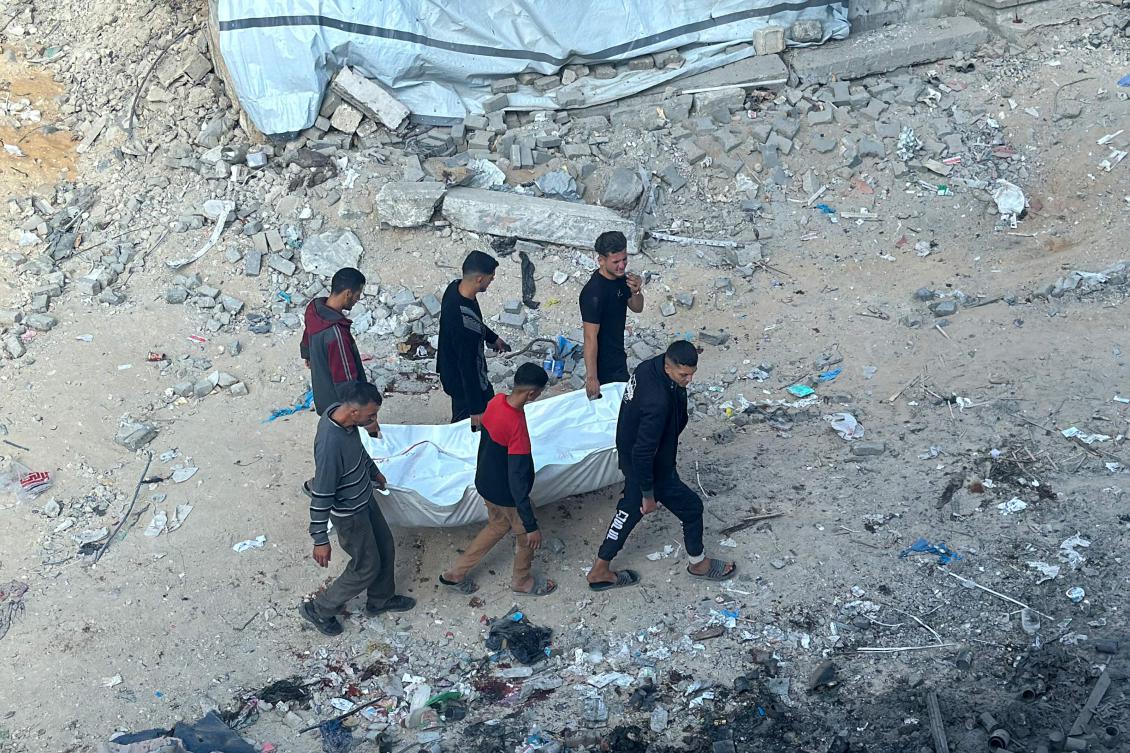 Palestinians carry the body of a man killed in an Israeli strike in Beit Lahia, northern Gaza Strip, on November 13. (AFP)