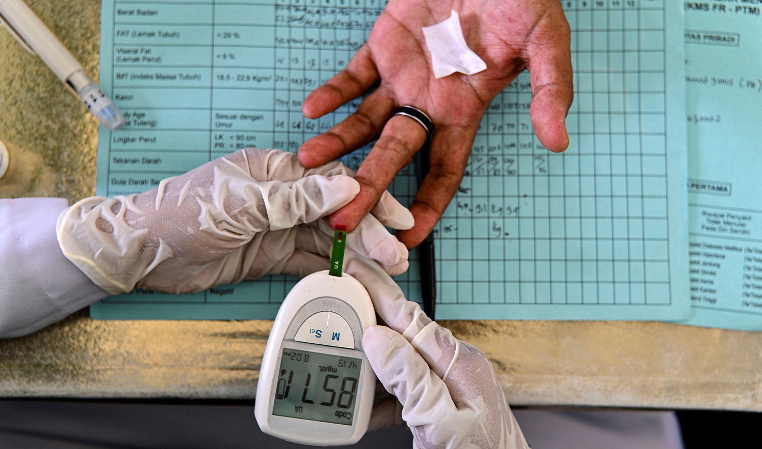 An elderly woman gets her blood tested during a drive to provide medical check-ups for hypertension, cholesterol and diabetes at an integrated services post in Banda Aceh on December 15, 2021. (AFP/File)