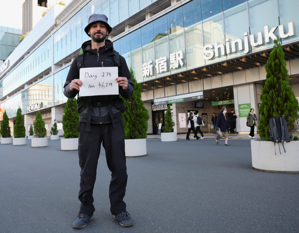 Omar Nok, a 30-year-old Egyptian who travelled from Cairo to Tokyo, holds a sign noting the days and distance he has travelled, in front of Shinjuku station in Tokyo, Japan. (Reuters)