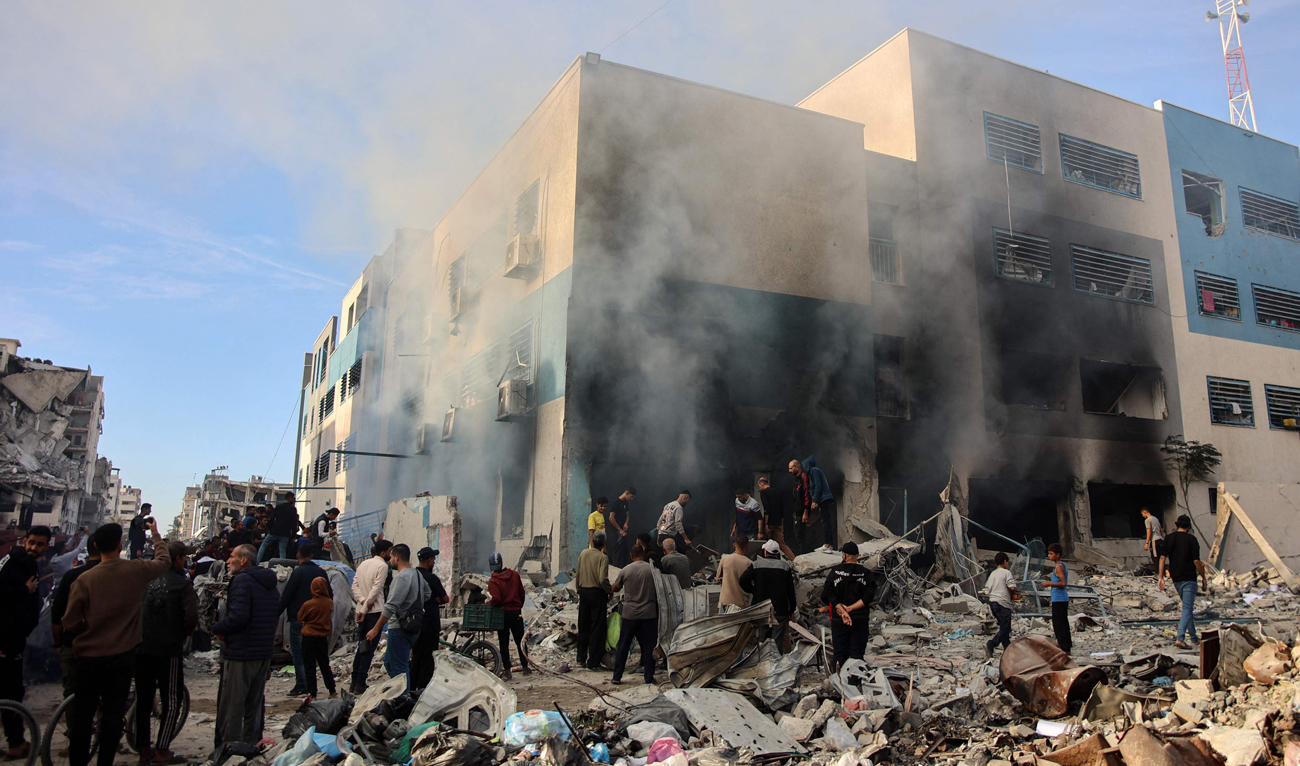People gather as smoke rises from a UN school-turned Shelter after it was hit in an Israeli strike, in the Rimal neighbourhood of Gaza City in the northern Gaza Strip on November 14, 2024, amid the ongoing war between Israel and the Hamas group. (AFP)