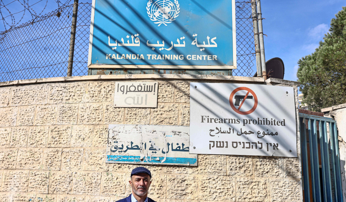 Baha Awaad, the principal of UNRWA's training centre, poses for a picture in front of the school's gate in the refugee camp of Qalandia, south of Ramallah, in the occupied West Bank on November 14, 2024. (AFP)