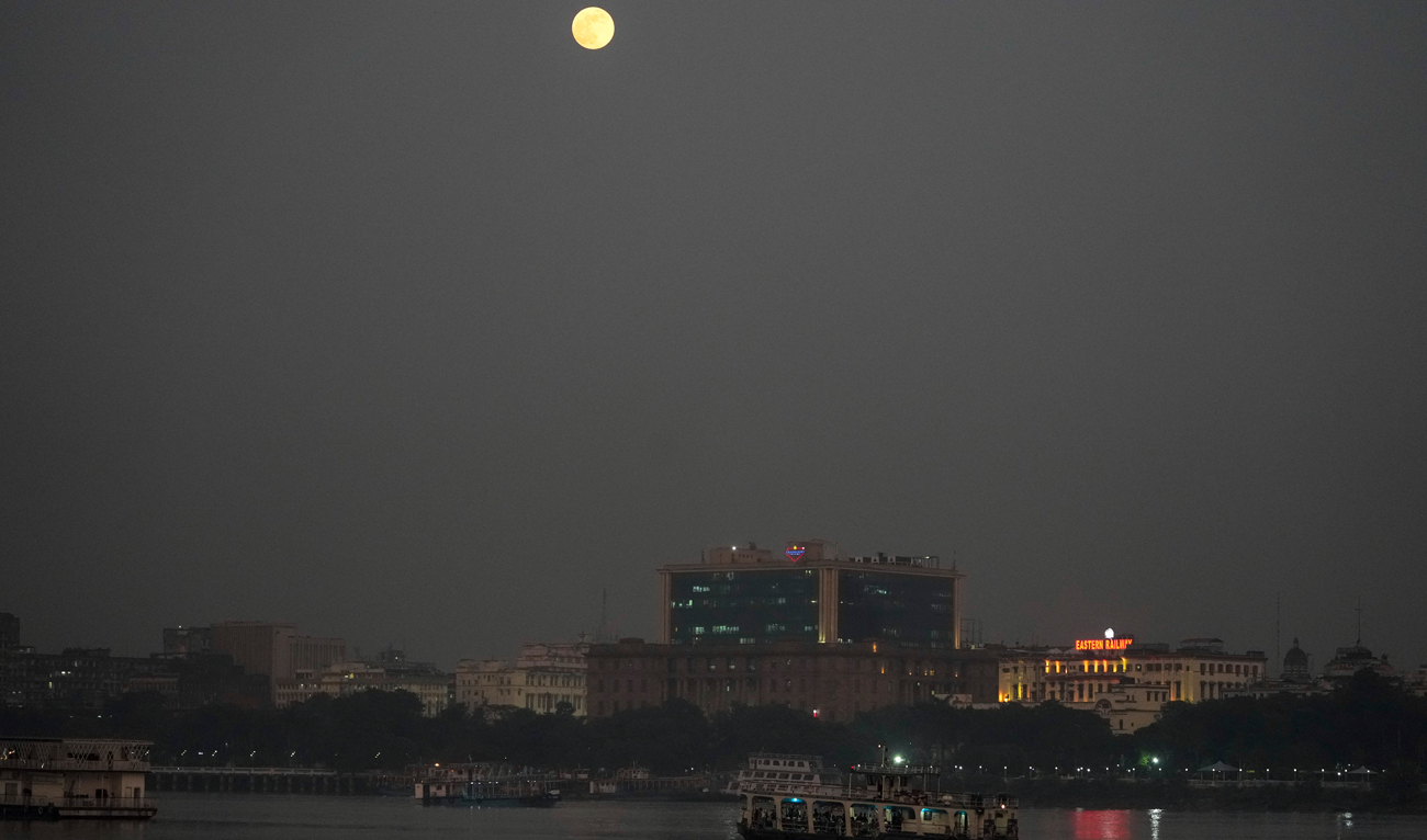 The super moon rises in the horizon as a passenger vessel cross the Hooghly River in Kolkata, India on November 15, 2024. (AP)