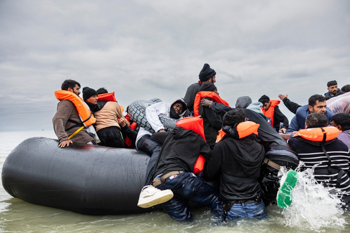 Migrants attempt to board a smuggler's inflatable dinghy in an attempt to cross the English Channel, on Ecault beach in Saint-Etienne-au-Mont, near Neufchatel-Hardelot, northern France on October 30, 2024