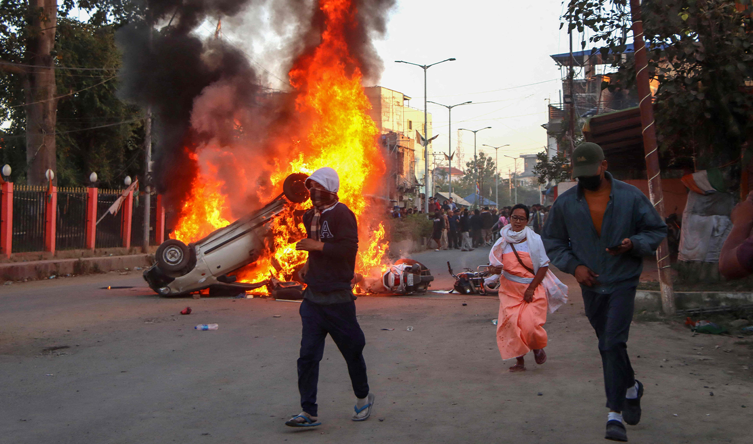 People run past burning vehicles of India's Bharatiya Janata Party (BJP) MLA during a protest to condemn the alleged killing of women and children in Imphal, capital of India's violence-hit northeastern state of Manipur on November 16, 2024. (AFP)