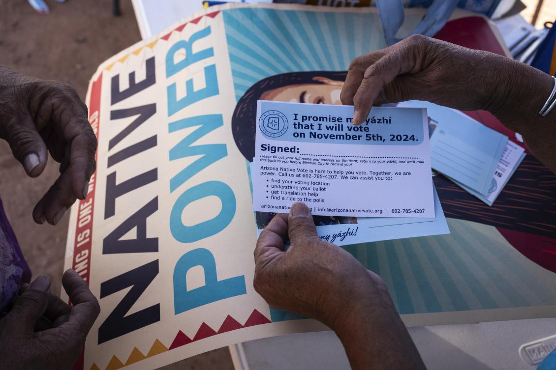 An organizer instructs a resident on how to properly fill out a pledge card. (AP)