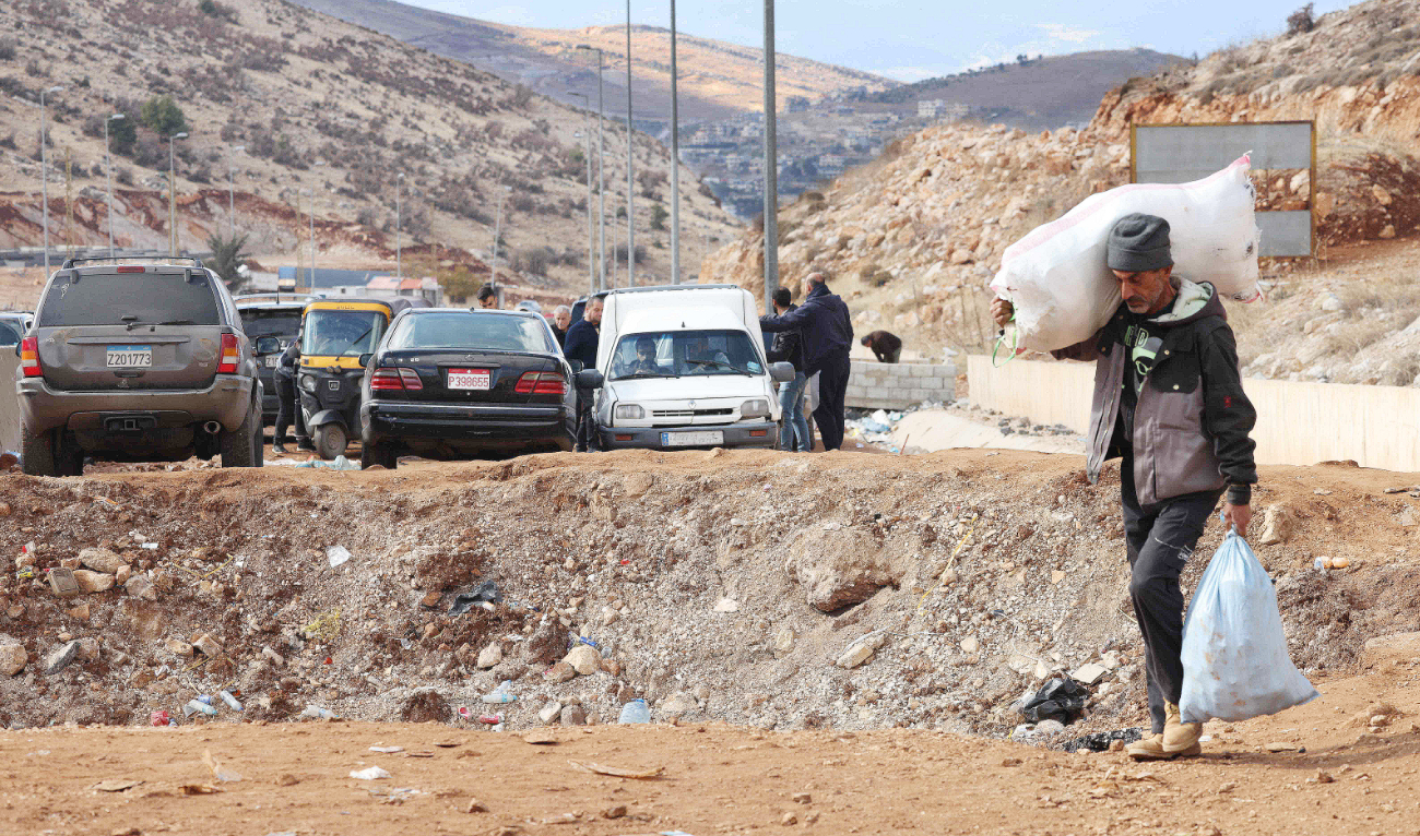A man fleeing Israeli bombardment crosses a crater, caused by an airstrike, in the area of Masnaa on the Lebanese side of the border crossing with Syria. (AFP)