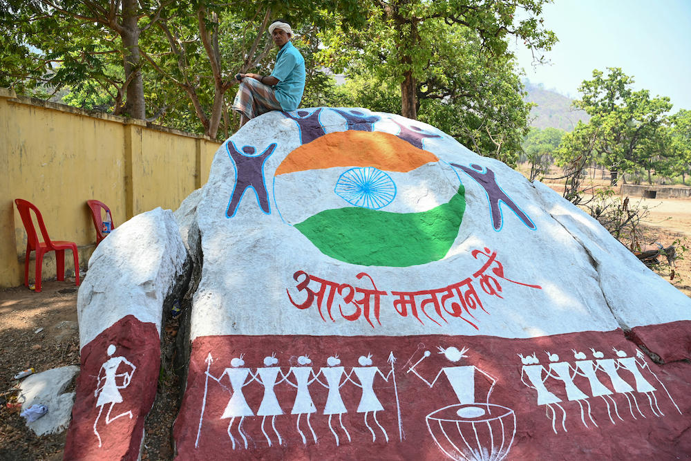 A resident sits on a boulder painted with voter awareness mural in Dugeli village of Chhattisgarh state, one of the last strongholds of the Naxal rebels, on April 19, 2024. (AFP file photo)