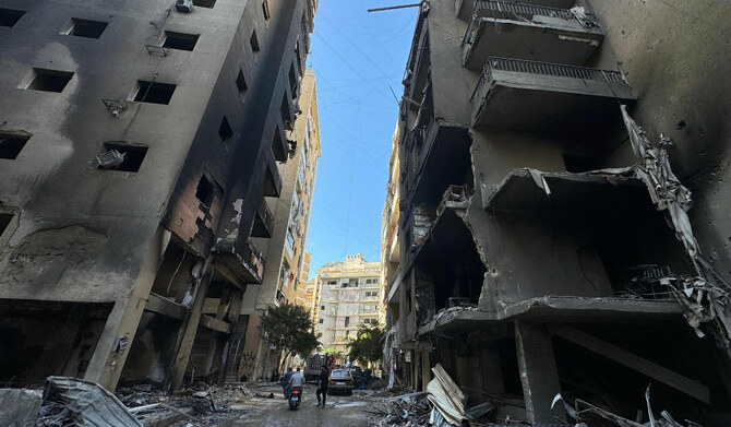 People walk between burned buildings at the site of an Israeli airstrike the previous night in Beirut’s southern Rweiss neighborhood on November 22, 2024, amid the ongoing war between Israel and Hezbollah. (AFP)