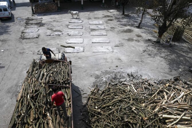 Labourers unload wood from a truck to be used for funeral pyres at a crematorium in New Delhi on May 11, 2021. (AFP/File)