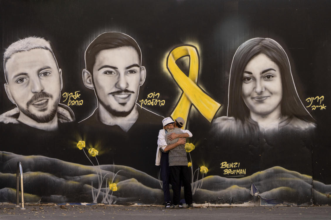 People hug next to graffiti portraits of Gaza-held hostages in Jerusalem, Nov. 22, 2024. (AP)