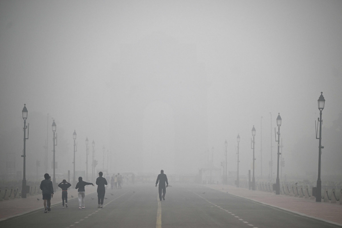 Pedestrians walk along the Kartavya Path engulfed in thick smog, near India Gate in New Delhi on November 18, 2024. (AFP)