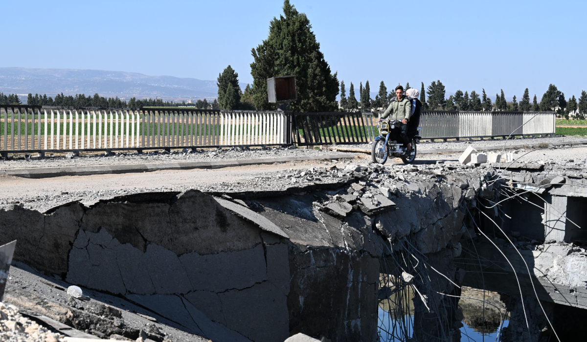 A couple cross on a motorcycle a bridge, damaged in an Israeli strike near the Syrian village of Tall al-Nabi Mando, in the countryside of Qusayr on October 28, 2024. (AFP)