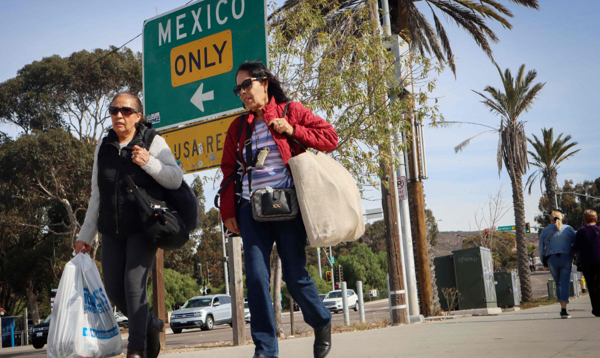 Shoppers walk with their purchases near the US-Mexico border in San Ysidro, California, on November 26, 2024. (AFP)